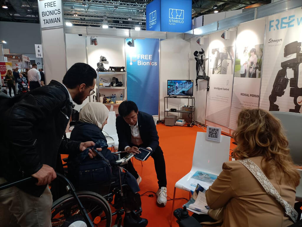 參加歐洲最大輔具照護展 REHACARE，為民眾介紹 AI 外骨骼機器人。